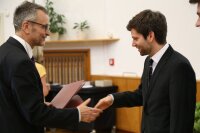 Der Dekan überreicht die Promotionsurkunden.