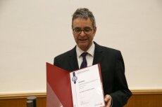 Der Dekan zeigt die Urkunde für den Friedrich-Hund-Dissertationspreis.